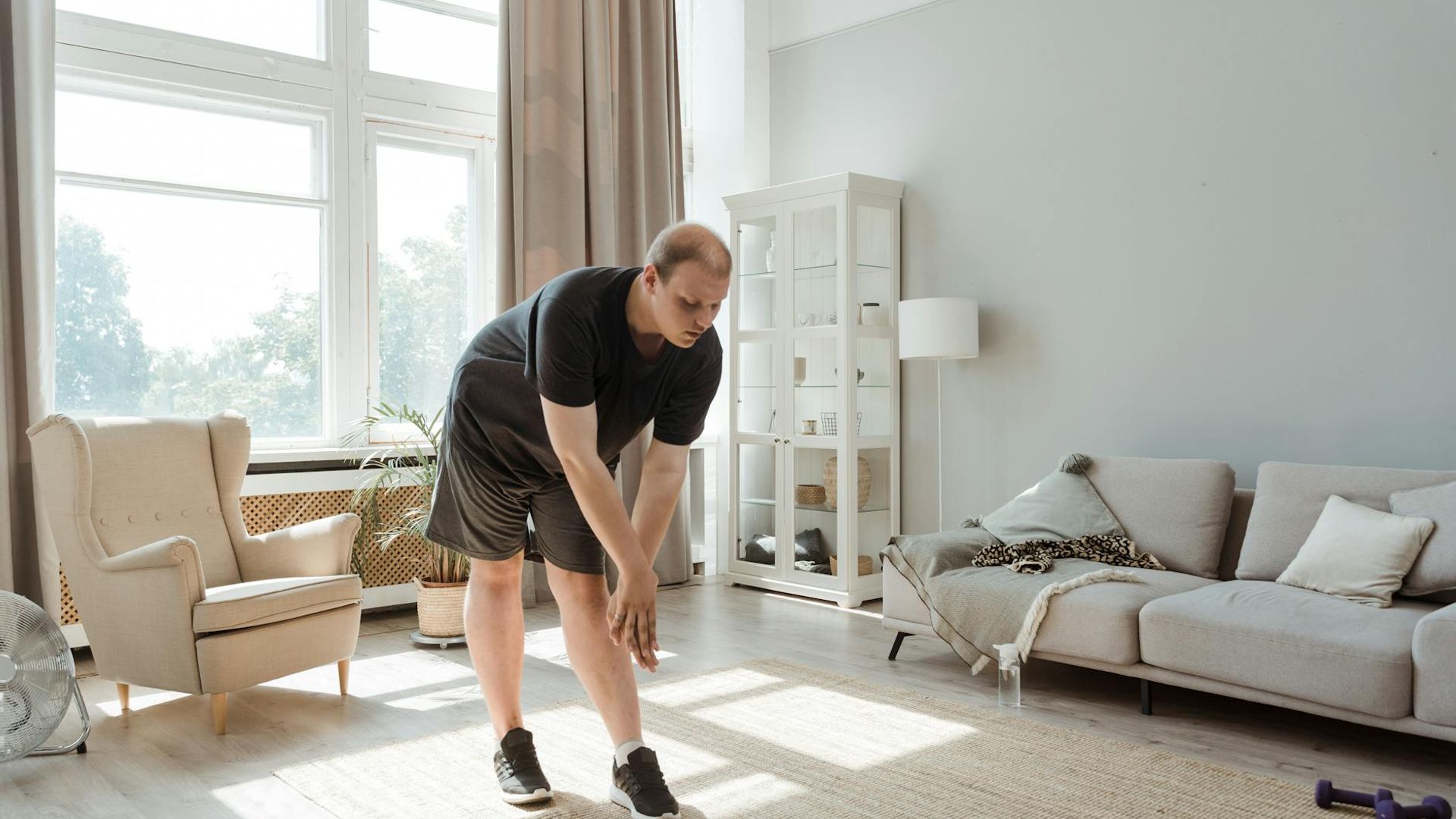A person performing light stretching exercises in a sunlit room